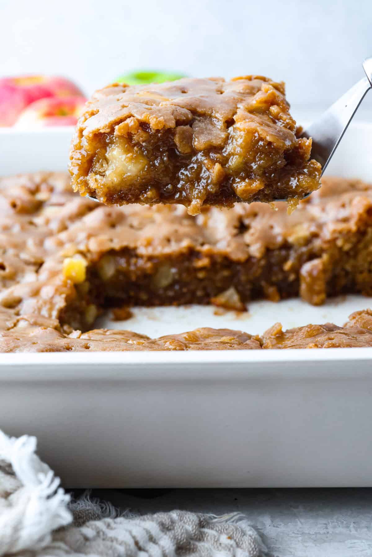 If you love cozy apple desserts, this apple dapple cake is going to be your new fall favorite. It’s packed with fresh apples and warm cinnamon, topped with a buttery caramel glaze that sinks right into the cake. Someone lifting a slice of apple dapple cake out of the baking dish.