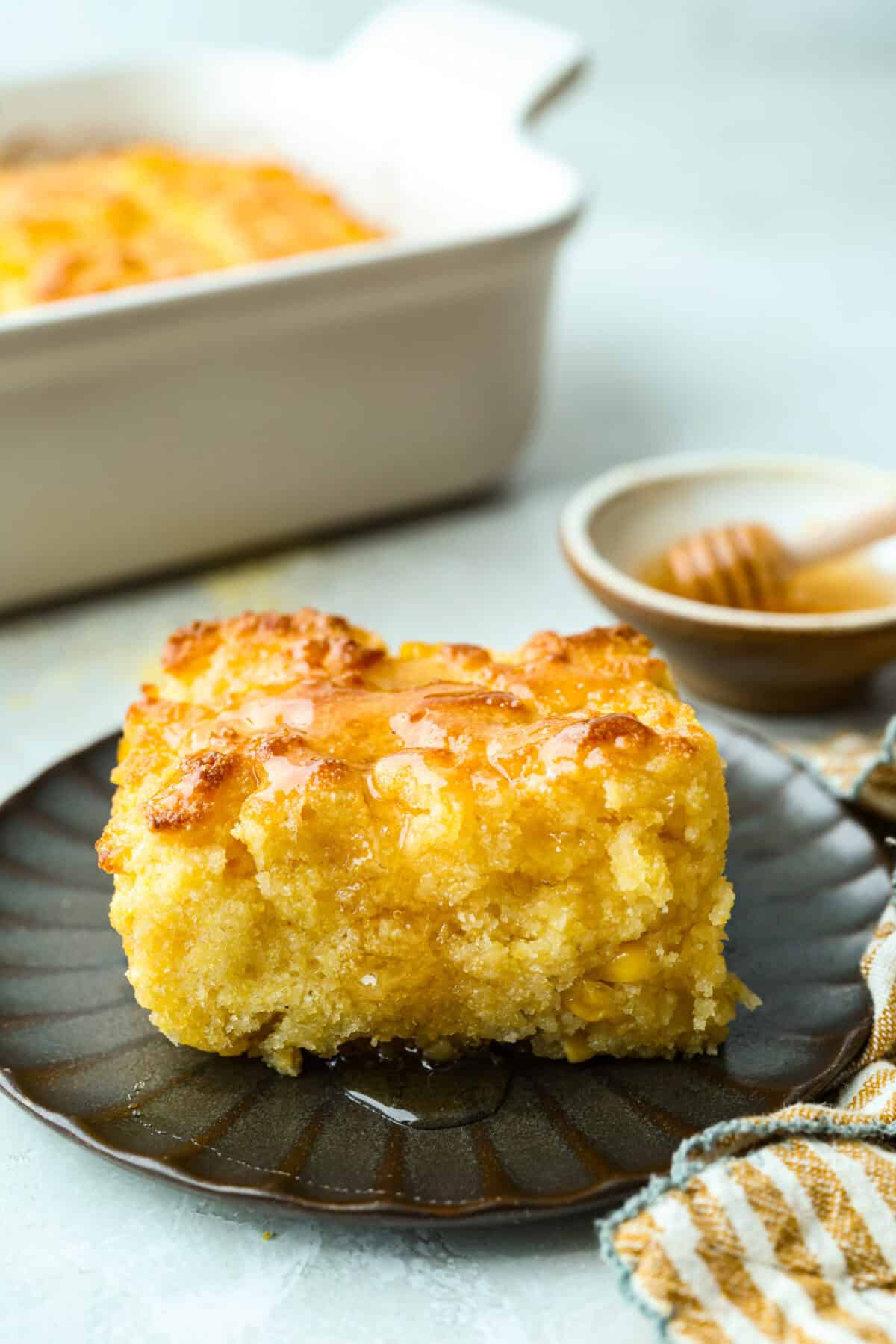 Butter swim cornbread bakes in a whole stick of butter for crisp, golden edges and a soft, tender center. My secret ingredient is a can of creamed corn, which makes it extra moist and adds even more sweet corn flavor. Slice of butter swim cornbread with a drizzle of honey.