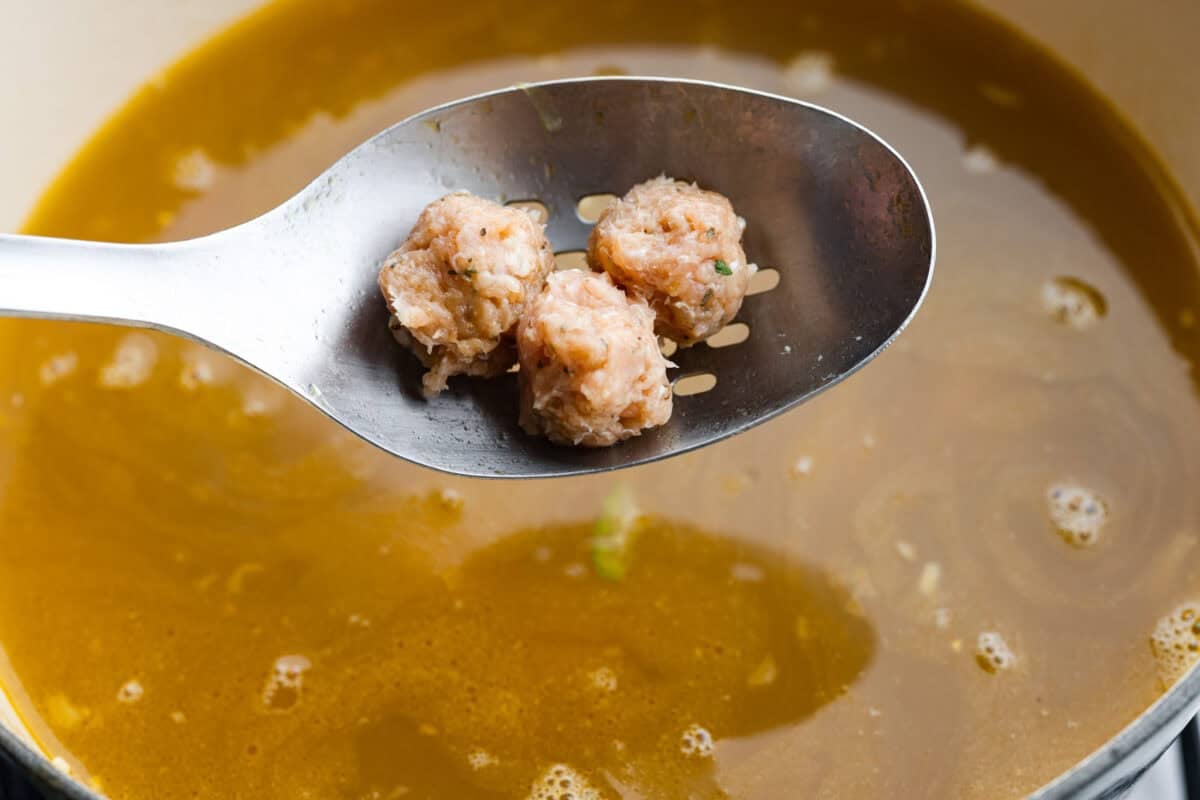 Meatballs being added to the soup. 