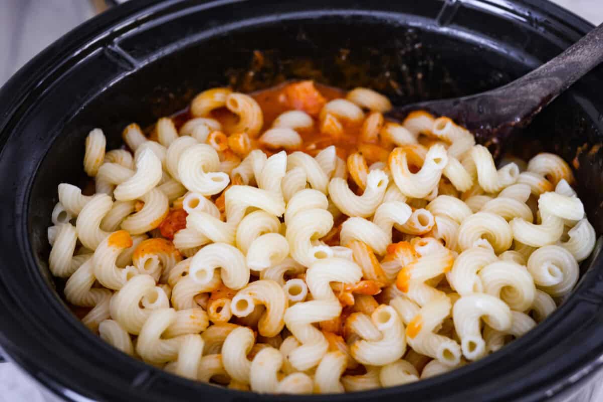 Crockpot creamy chicken pasta is the kind of dinner I need on a busy weeknight! Tender chicken cooks all day in a creamy marinara sauce, then you stir in pasta and cheese for the easiest comfort food dinner. Cooked pasta added to the shredded chicken and pasta sauces in the crockpot.