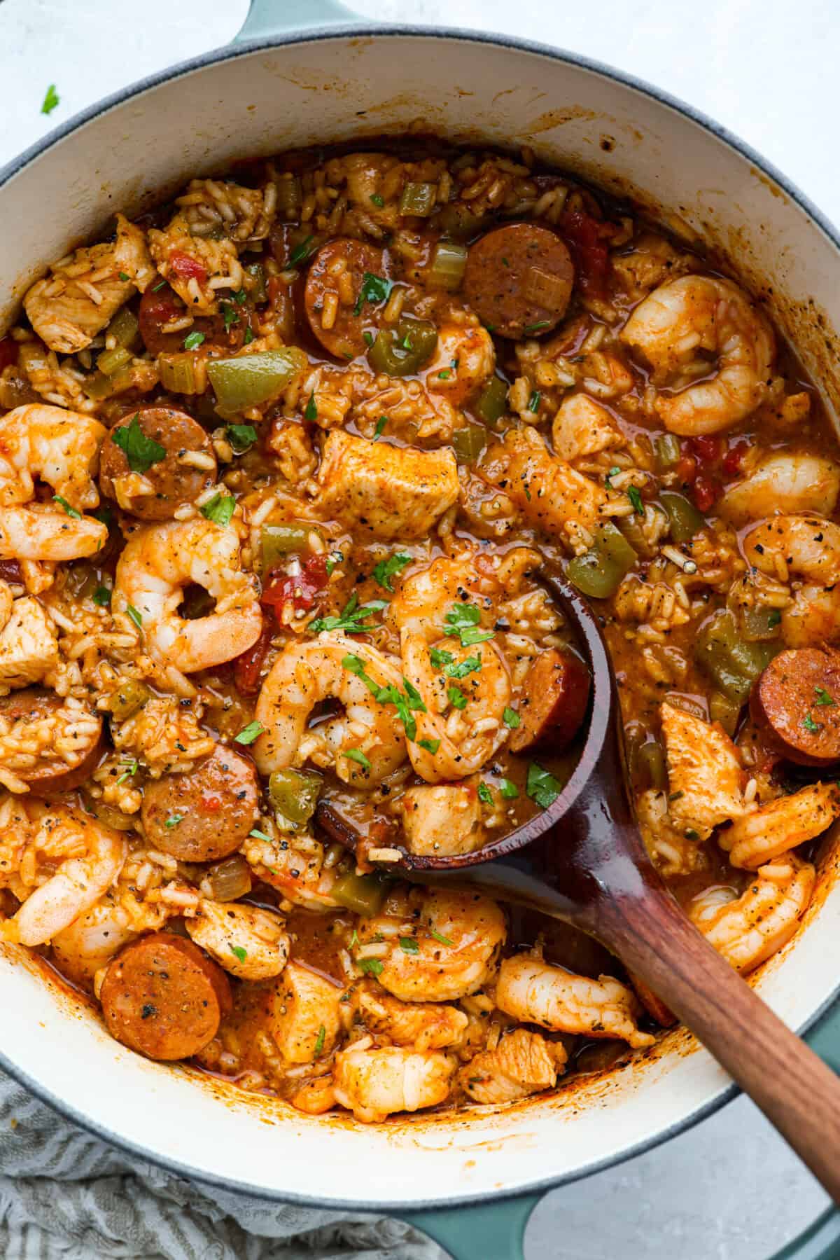 Cooked jambalaya in a pot with a wooden spoon. 