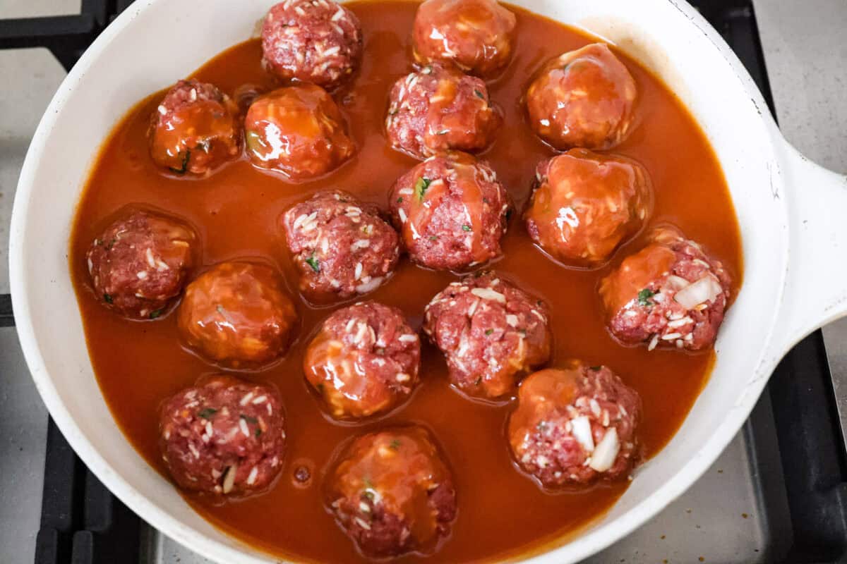 Porcupine Meatballs are juicy, well-seasoned meatballs with tender rice simmered in a rich, tangy tomato sauce. This recipe comes straight from my grandma’s kitchen, and trust me, your family’s about to be obsessed! Sauce poured over meatballs in the skillet.