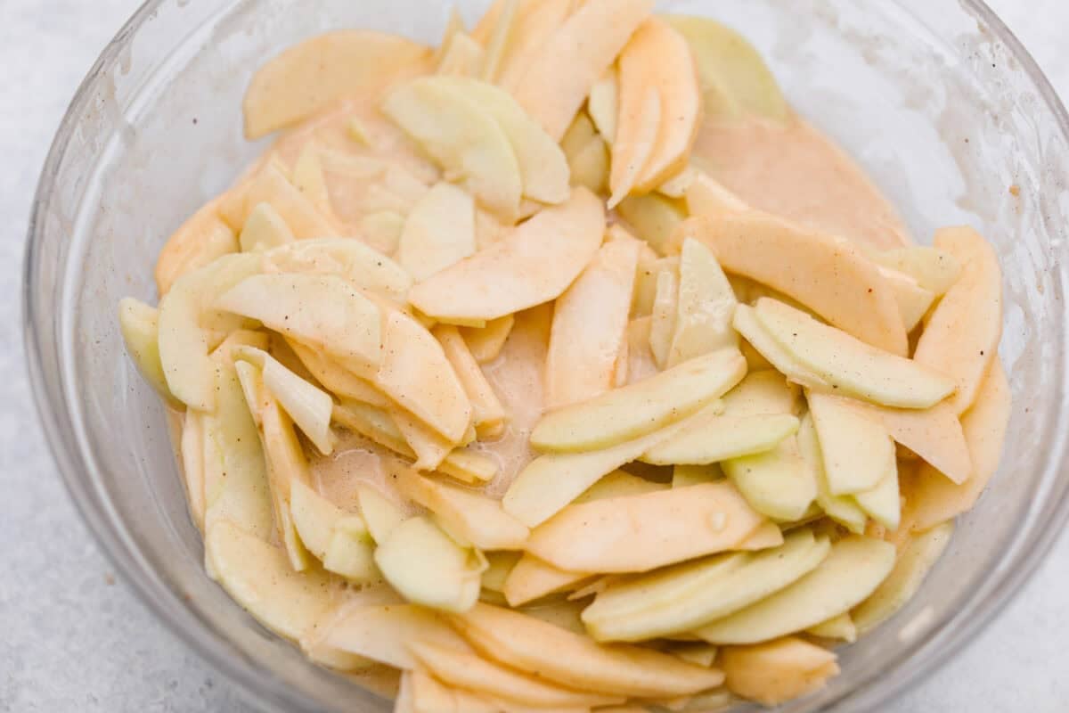 This invisible apple cake is a little magical! Paper-thin apple slices are coated in a simple, lightly spiced batter, then layered in a loaf pan and baked into a tender, custardy cake. Such a delicious way to enjoy fresh apples! Thinly sliced apples coated in the batter.