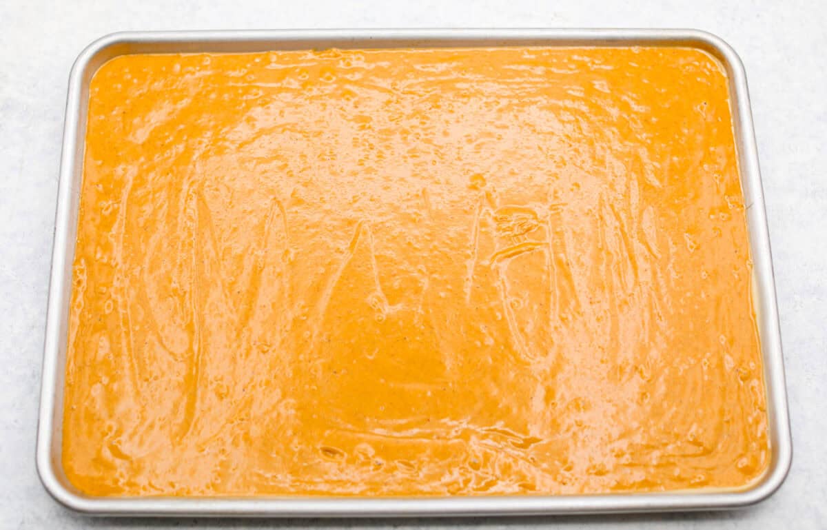 Pumpkin Sheet Cake Bars are one of my oldest son’s favorite desserts, and honestly, I get it! They’re incredibly moist and fluffy, full of warm pumpkin spice, and topped with the best cream cheese frosting. Batter poured into a jelly roll sheet pan read to be baked.