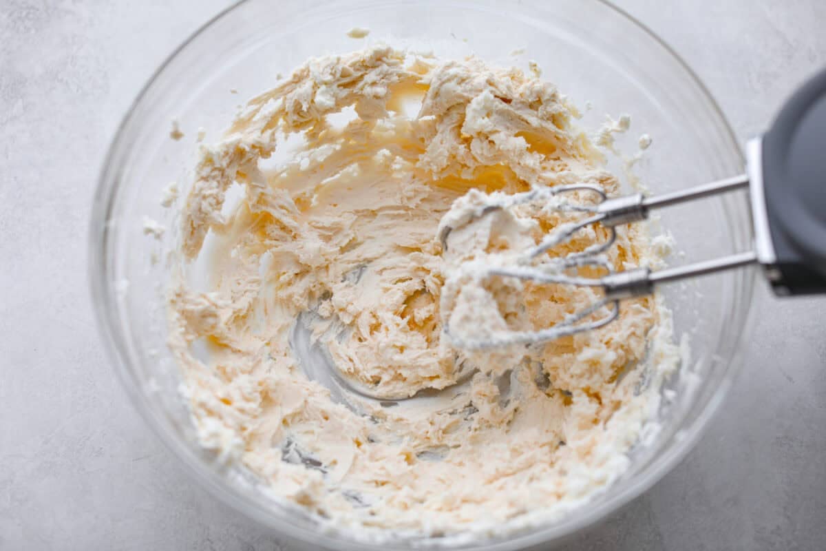 Pumpkin Sheet Cake Bars are one of my oldest son’s favorite desserts, and honestly, I get it! They’re incredibly moist and fluffy, full of warm pumpkin spice, and topped with the best cream cheese frosting. Cream cheese being beaten with a hand mixer.