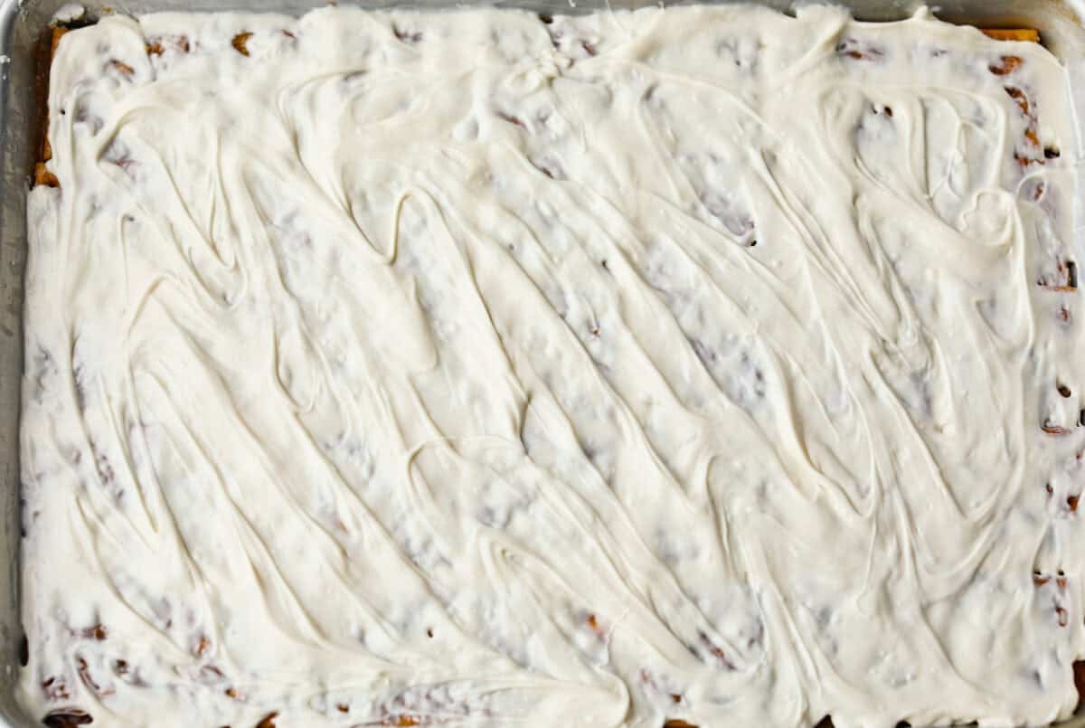 Pumpkin spice crack is Christmas crack with a fall twist! Buttery toffee, salty crackers, white chocolate, pumpkin pie spice, and crunchy praline pecans make this an easy treat you won’t be able to stop snacking on. Melted white chocolate spread out.
