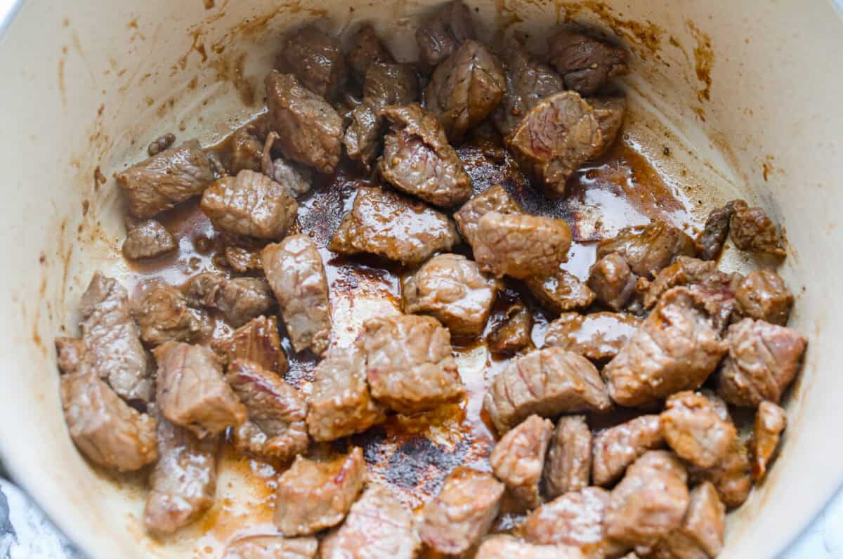 Beef browning in the bottom of a dutch oven.