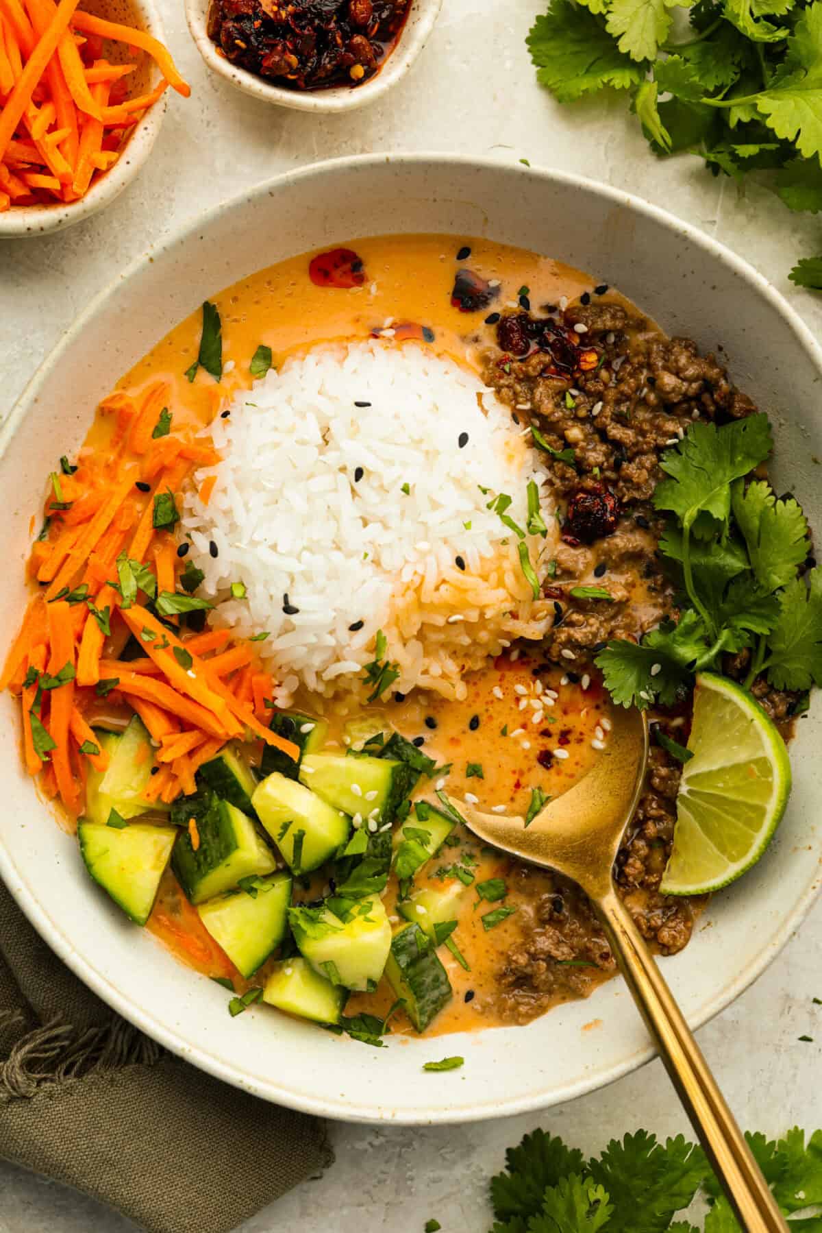 Top down shot of a beef broth bowl garnished with lime, chili crisp, and cilantro. 