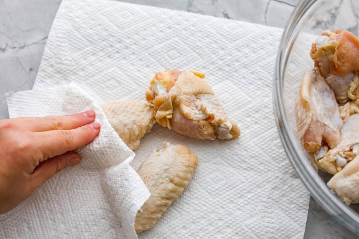 Someone patting the chicken wings dry with paper towels.