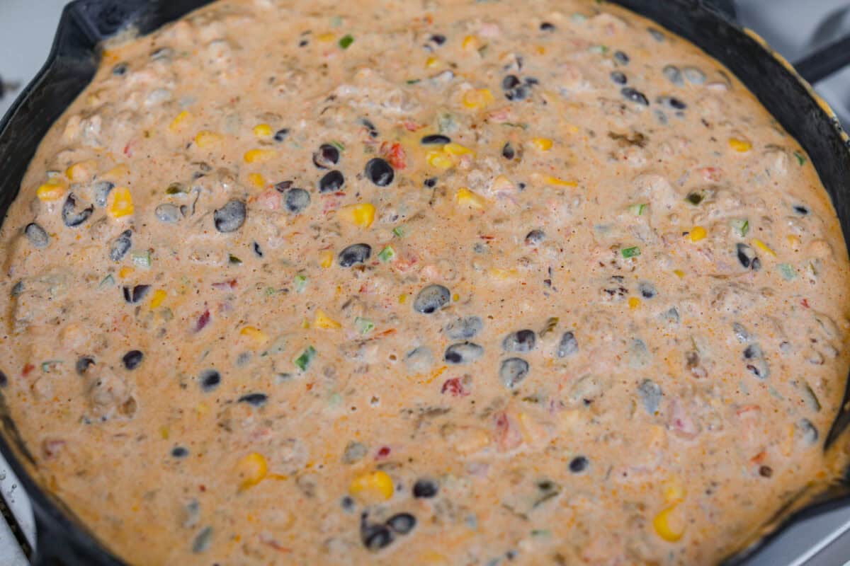 My hot cowboy dip is what I'm bringing to the next game day party! It's loaded with savory sausage, gooey cheese, and a little kick from the jalapeños. Everything comes together in one skillet, so there's less cleanup and more time to dig in! All of the ingredients melted and mixed together.