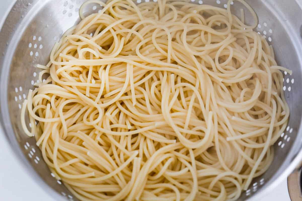 This Mississippi chicken spaghetti gives classic Mississippi chicken a cheesy pasta upgrade! Tender chicken, tangy pepperoncini peppers, ranch, and melty Colby Jack come together with spaghetti for an easy slow cooker dinner packed with flavor. Spaghetti noodles cooked and draining in a colander.