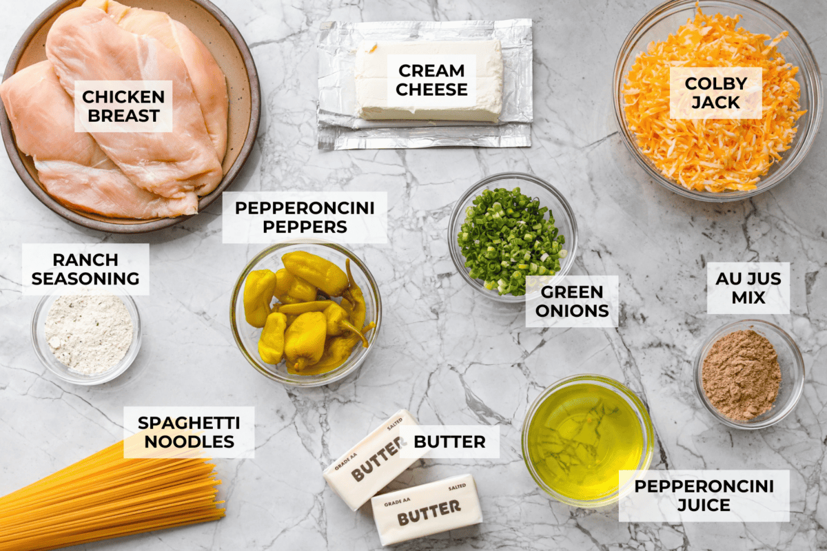 This Mississippi chicken spaghetti gives classic Mississippi chicken a cheesy pasta upgrade! Tender chicken, tangy pepperoncini peppers, ranch, and melty Colby Jack come together with spaghetti for an easy slow cooker dinner packed with flavor. Overhead shot of labeled Mississippi chicken spaghetti ingredients.
