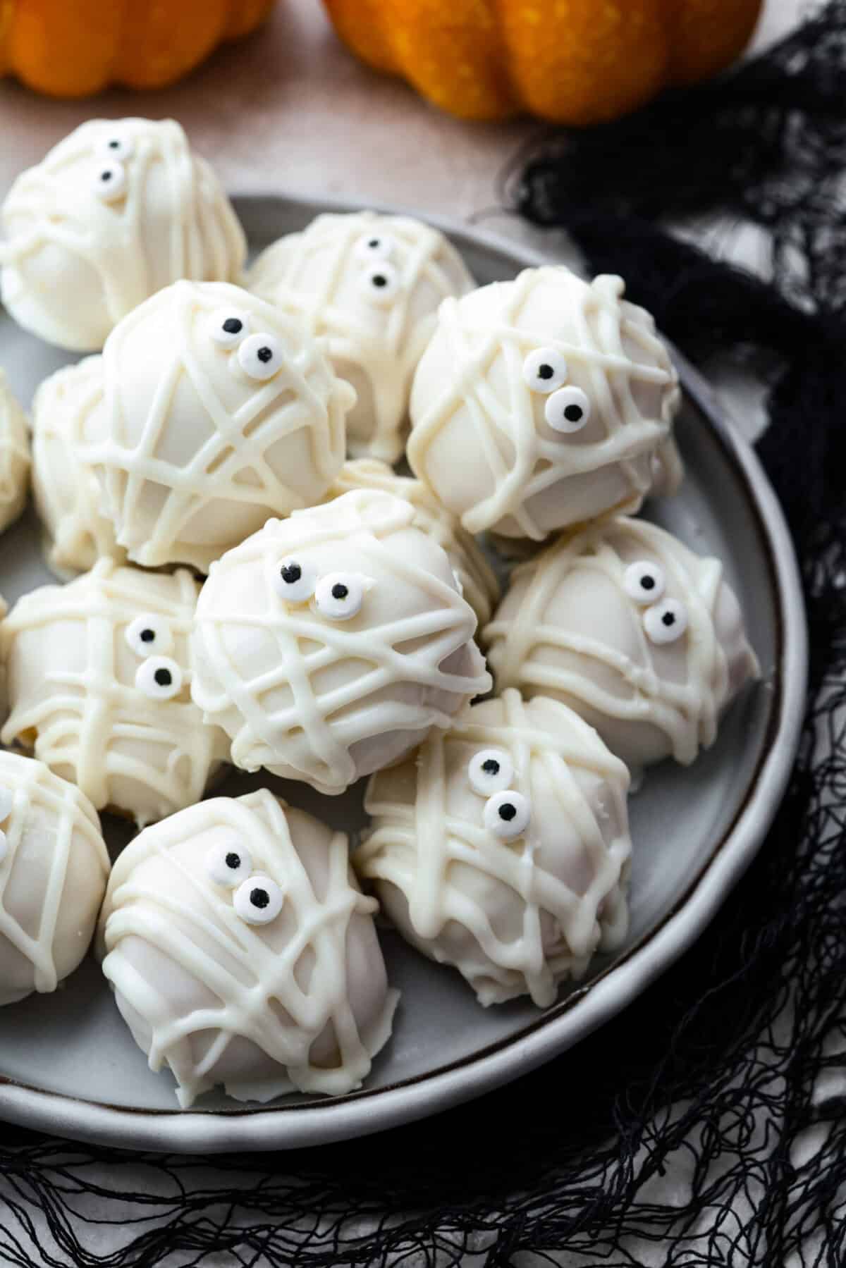 Mummy Oreo Balls are the cutest no-bake treat for Halloween! Golden Oreos and cream cheese make the creamy truffle center, then each one gets dipped in white chocolate and decorated with candy eyes and mummy “bandages.”