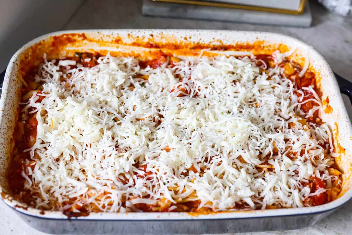 This no boil spaghetti bake makes pasta night SO easy! Everything goes straight into one baking dish, uncooked spaghetti included, then bakes under a layer of melty mozzarella for a cozy, cheesy dinner with hardly any prep. Cheese added to the top of the baked spaghetti.
