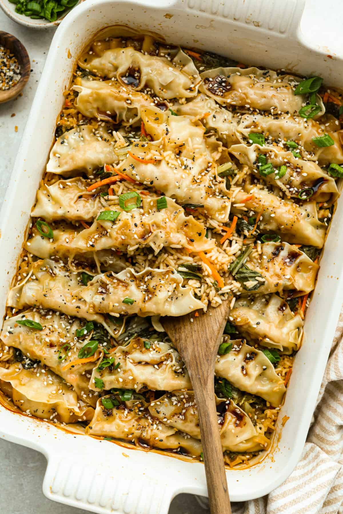 Baking dish with saucy potsticker and rice bake garnished with green onions and sesame seeds. 
