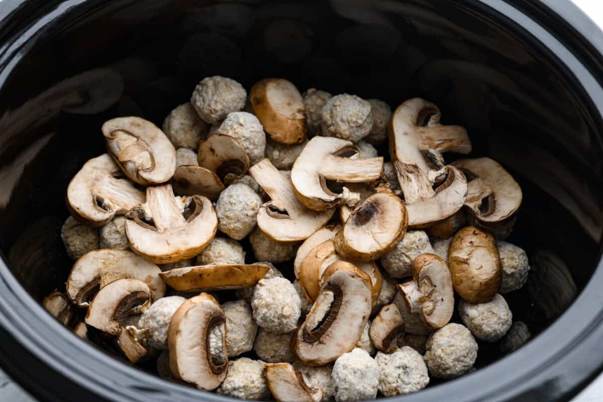 Frozen meatballs and mushrooms added to the slow cooker. 