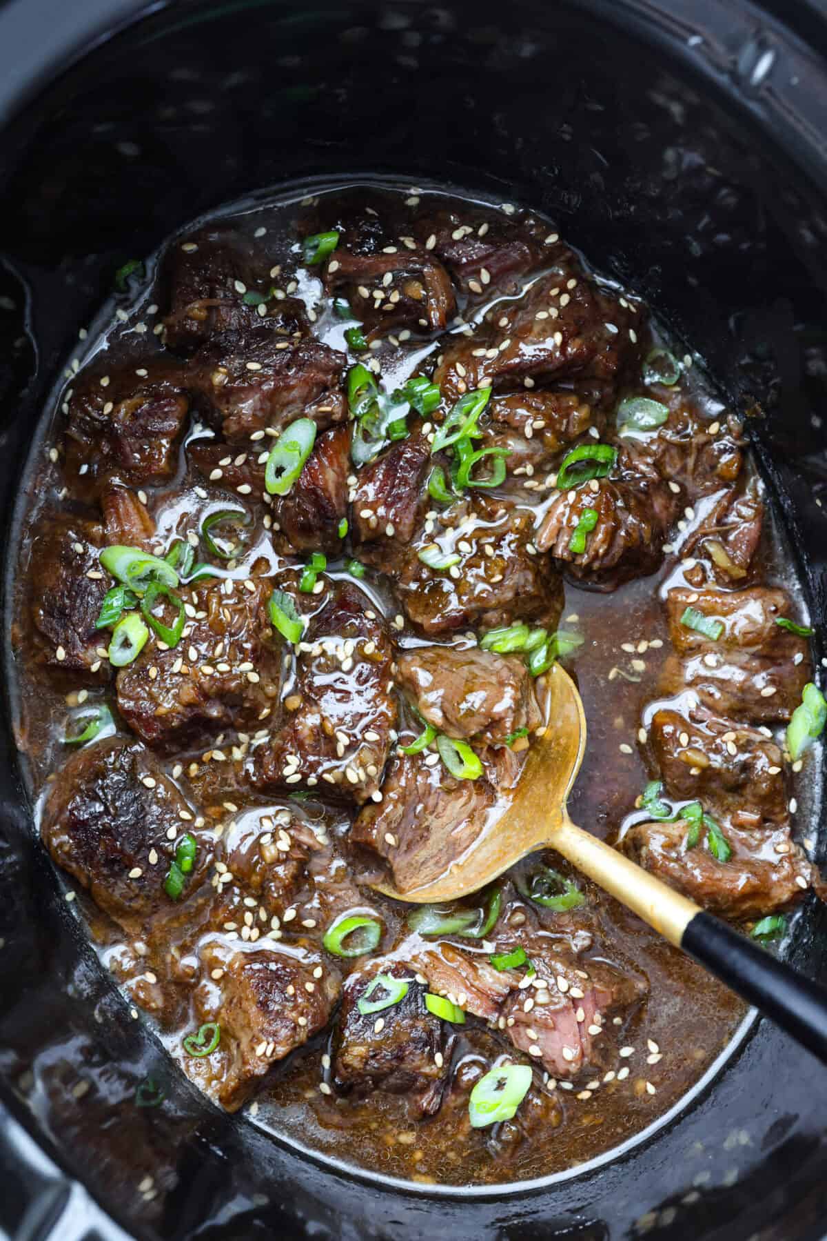 I love a good takeout-inspired dinner, especially when my slow cooker does most of the work! My slow cooker sesame ginger beef is packed with sweet and savory flavor, and the chuck roast cooks until it's perfectly tender. Top down shot of slow cooker sesame ginger beef in a crockpot garnished with sesame seeds and green onions.